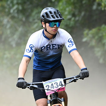 Student racing on a mountain bike. Links to Gifts by Estate Note