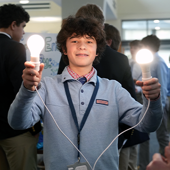 Student holding light bulb experiment. Links to Donor-Advised Funds