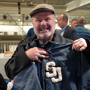 Alumni holding letterman jacket. Links to Gifts That Protect Your Assets