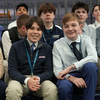 Group of students sitting in bleachers with two students in front smiling. Links to Gifts of Life Insurance