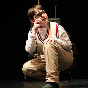 A student holding a magnifying glass. Links to Gifts of Cash, Checks, and Credit Cards